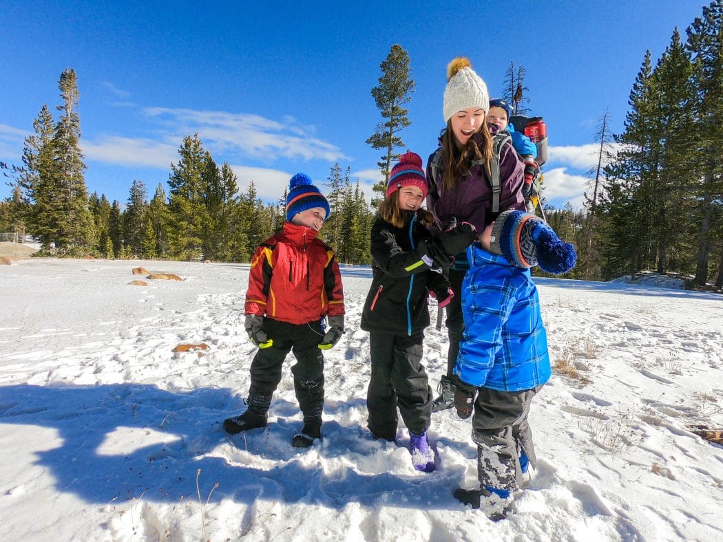 mom and kids playing together in the snow with warm coats on