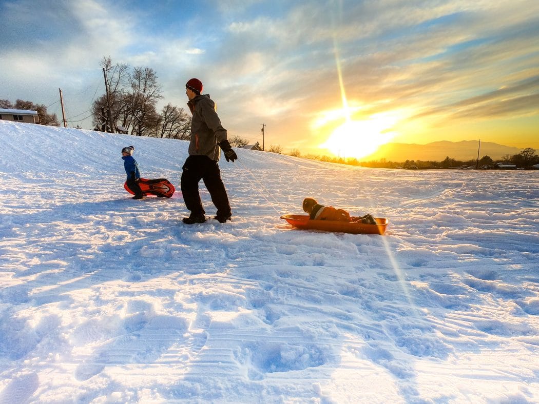 family sledding at sunset