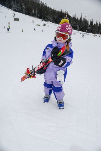 little girl carrying skis