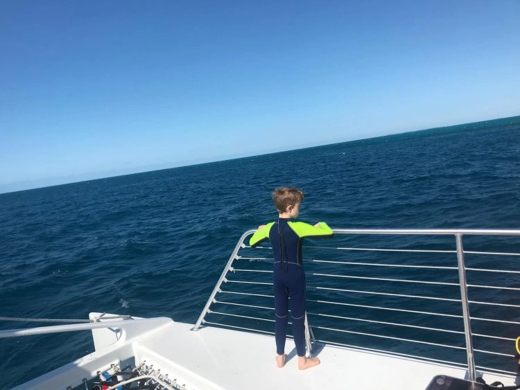 boy wearing a long wetsuit at sea