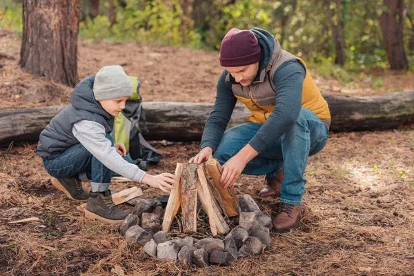 Father and son preparing a campfire Father and son preparing firewood to start their campfire